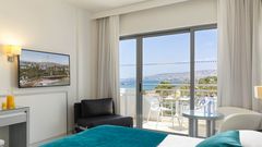 Modern eingerichtetes Zimmer mit Balkon und traumhaftem Blick über das tiefblaue Meer bis hin zur malerischen Küste.