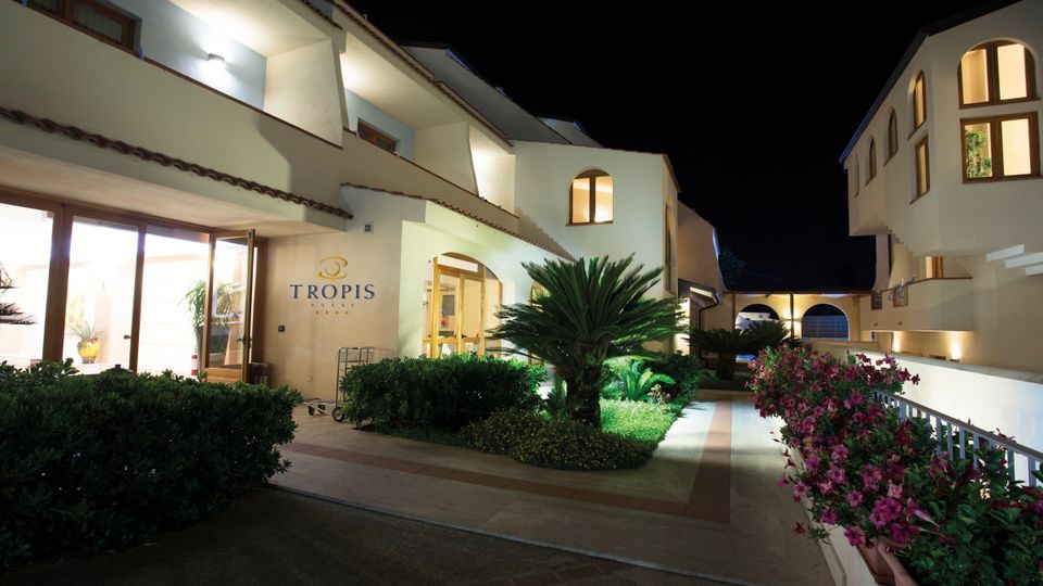 Stimmungsvoll beleuchteter Hoteleingang bei Nacht – mediterranes Ambiente mit gepflegter Gartenanlage.