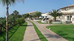 Weitläufige, gepflegte Gartenanlage mit mediterranem Flair und kleinen Wegen, die durch das Resort führen.