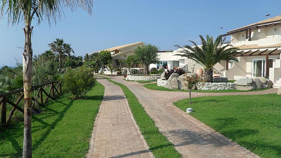 Weitläufige, gepflegte Gartenanlage mit mediterranem Flair und kleinen Wegen, die durch das Resort führen.