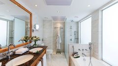 Helles, elegantes Bad mit Doppelwaschbecken, moderner Dusche und einladender Badewanne für entspannte Momente.