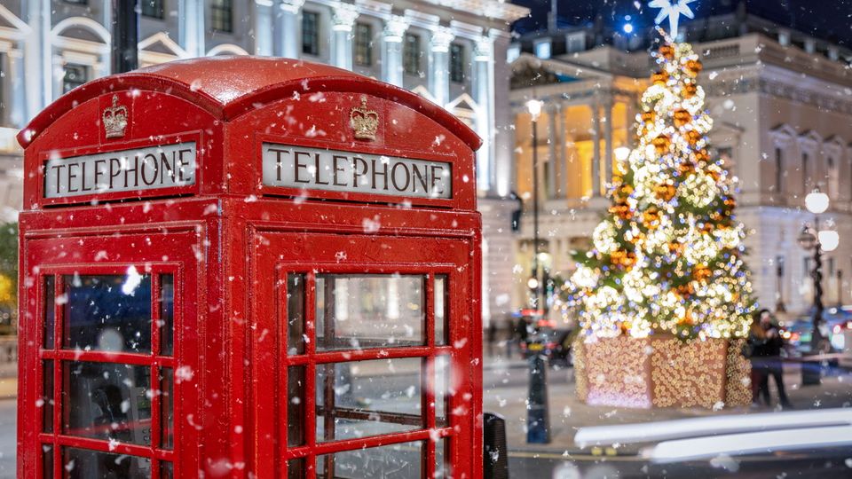 Rote Telefonzelle in London vor einem beleuchtetem Weihnachtsbau