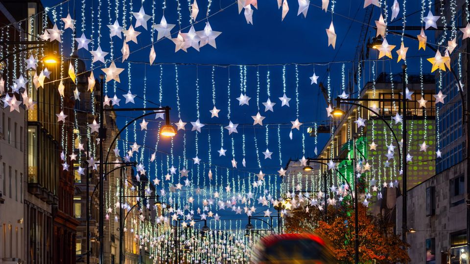 Festive Christmas decorations in the streets of London with red bus traffic during night time