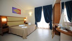 Freundlich eingerichtetes Doppelzimmer mit hellen Farben, gemütlichem Bett und Schreibtisch – ideal zum Entspannen nach einem Urlaubstag.